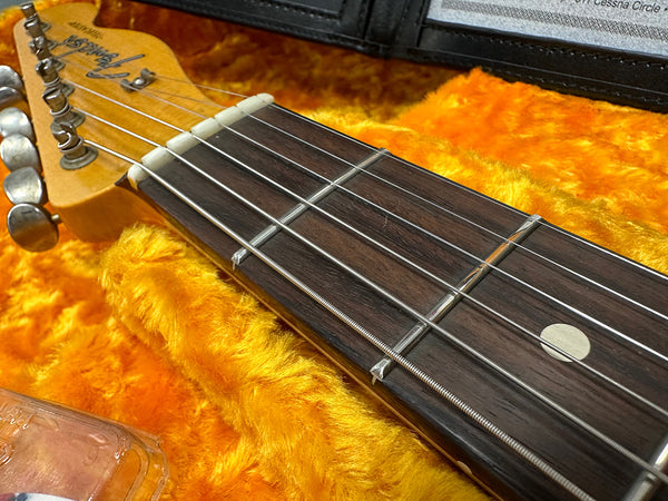 Close-up of Fender Stratocaster electric guitar headstock and fretboard with steel strings in yellow plush-lined hard case