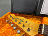 Close-up of Fender Telecaster guitar headstock with tuning pegs inside an orange plush-lined guitar case