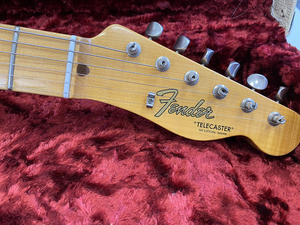 Close-up of Fender Telecaster electric guitar headstock with tuning pegs on red plush guitar case interior