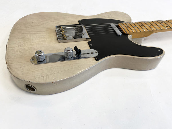 Close-up of vintage white electric guitar with crackled finish and black pickguard, showing chrome control knobs and bridge on white background