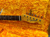 Close-up of Fender Telecaster guitar headstock with tuning pegs on bright orange plush guitar case interior