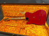 Red Fender electric guitar with worn finish, laid in vintage orange plush-lined hard case, showing back and neck details