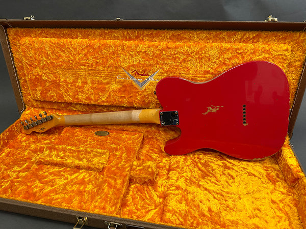 Red Fender electric guitar with worn finish, laid in vintage orange plush-lined hard case, showing back and neck details