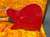 Back of red Fender electric guitar with visible wear and chip marks resting in orange plush-lined Fender guitar case