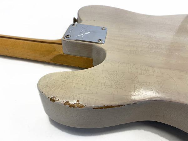 Close-up of vintage white electric guitar body with neck plate and visible wear on edge showing wood underneath the cracked finish