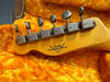 Vintage Fender Custom Shop guitar headstock with metal tuning pegs in a bright orange plush guitar case interior