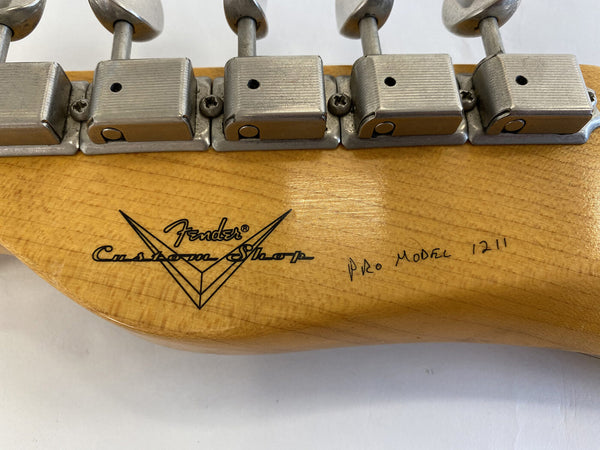 Close-up of Fender Custom Shop guitar headstock with vintage-style tuning pegs and handwritten "Pro Model 1211" marking on natural wood finish