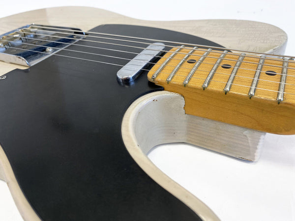 Close-up of vintage white electric guitar body with black pickguard and maple fretboard showing wear and aging details