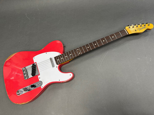 Vintage red Fender Telecaster electric guitar with white pickguard and rosewood fretboard on gray background
