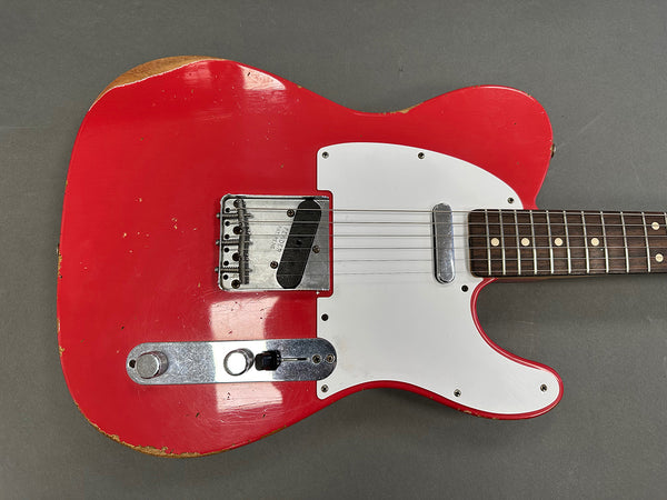 Close-up of red vintage Fender Telecaster electric guitar body with white pickguard, metal bridge plate, and rosewood fretboard, showing wear and aging.