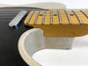 Close-up of neck joint and fretboard with metal frets on electric guitar with black body and cream pickguard on white background