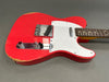 Red electric guitar with white pickguard and chrome hardware showing worn finish around the edges and vintage-style control knobs on gray background