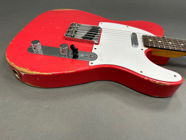 Red electric guitar with white pickguard and chrome control knobs showing worn edges and vintage finish