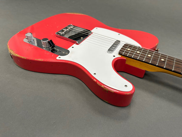 Close-up of red vintage electric guitar body with white pickguard, chrome hardware, and visible wear on edges, displayed on gray background