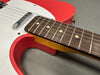 Close-up of red and white electric guitar body showing rosewood fretboard and chrome pickup on gray background