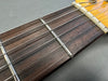 Close-up of acoustic guitar fretboard with metal frets and strings on rosewood fingerboard against gray background