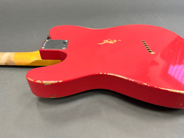 Close-up of red electric guitar body with worn finish and visible paint chips on gray background