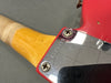 Close-up of serial number R109398 on chrome neck plate attached to red electric guitar body with natural wood neck and visible screw heads