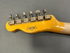 Close-up of vintage Fender Custom Shop electric guitar headstock with six metal tuning pegs on grey background