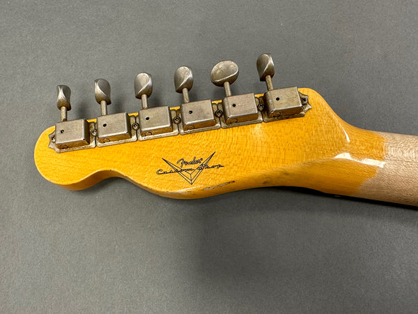 Close-up of vintage Fender Custom Shop electric guitar headstock with six metal tuning pegs on grey background