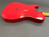 Red electric guitar body with visible wear and chips on the finish, showing a natural wood edge on a gray background