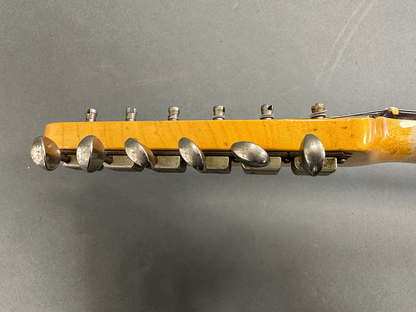 Vintage guitar headstock close-up showing tuning pegs and aged maple wood neck on gray background