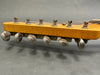 Close-up image of vintage guitar headstock with six metal tuning pegs and wrapped strings on light wood finish