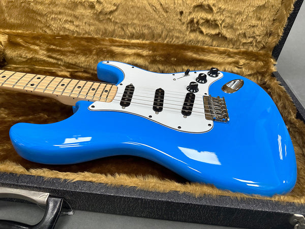 Electric blue solid body electric guitar with white pickguard and maple neck in a plush brown guitar case