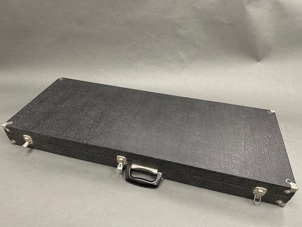 Closed black rectangular guitar case with metal corner protectors and latch locks on a gray background