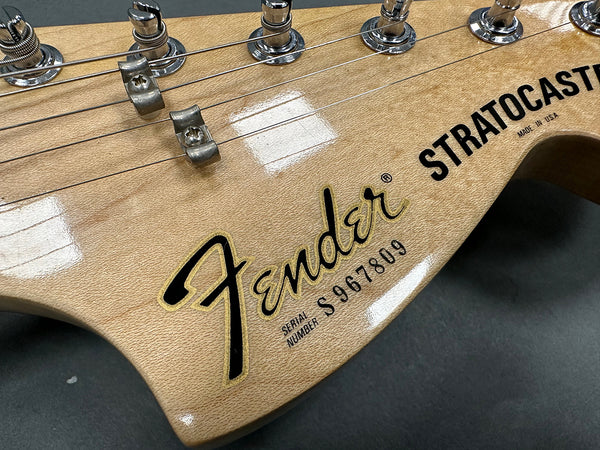Close-up of Fender Stratocaster guitar headstock with serial number S967809 and tuning pegs, made in USA, natural wood finish