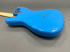 Back view of bright blue electric guitar body with wooden neck on gray surface