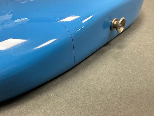 Close-up of blue electric guitar body side showing strap button and a visible crack detail on the finish near the joint.