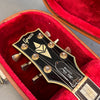 Close-up of Greco Les Paul Custom guitar headstock with vintage tuning pegs inside red velvet-lined brown guitar case