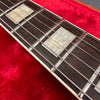 Close-up of guitar fretboard with pearl block inlays and steel strings on red plush surface