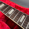 Close-up of electric guitar rosewood fretboard with rectangular pearl inlays and metal frets on red plush case lining