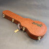 Brown Gibson hard guitar case with gold latches and handle on gray background