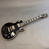 Epiphone Les Paul electric guitar in black with gold hardware and cream binding lying on gray surface