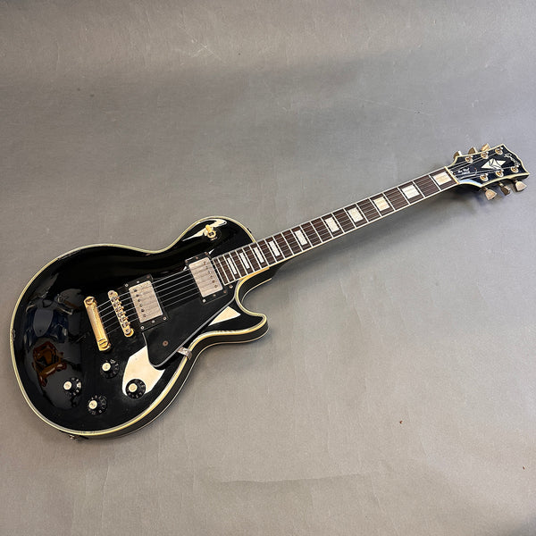 Epiphone Les Paul electric guitar in black with gold hardware and cream binding lying on gray surface