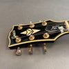 Close-up of vintage Greco guitar headstock with gold tuning pegs and "Super Real Custom" label on black background