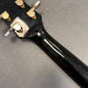 Close-up of black guitar neck and headstock showing gold Greco tuning pegs on a gray background