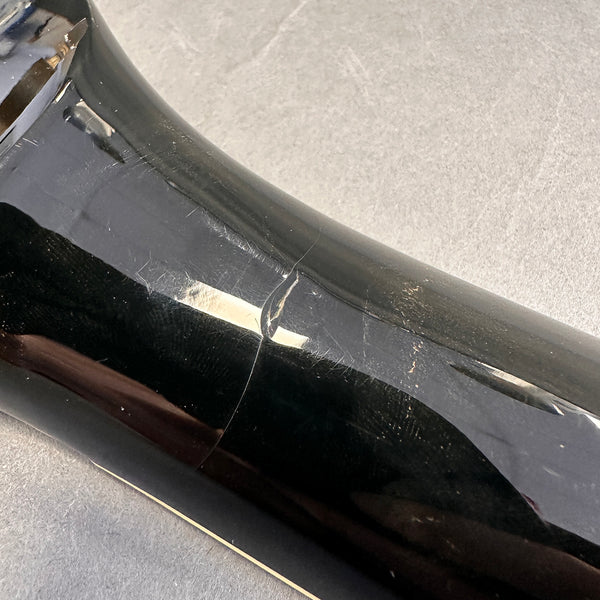 Close-up of black guitar body with visible crack and surface scratches on glossy finish