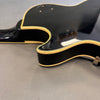 Close-up of black electric guitar body with cream binding and glossy finish on gray background