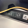 Close-up of digital scale showing guitar weight of 4.726 kilograms with part of guitar body visible, Coffee House Guitars product image.