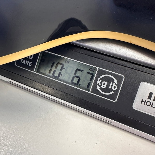 Close-up of a guitar body edge resting on a digital scale displaying a weight of 10 pounds 6.7 ounces