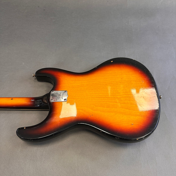 Vintage sunburst electric guitar body back view showing wear and chrome neck plate on gray background