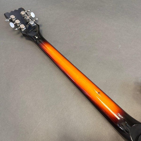 Back of guitar neck with sunburst finish and chrome tuning pegs on gray background