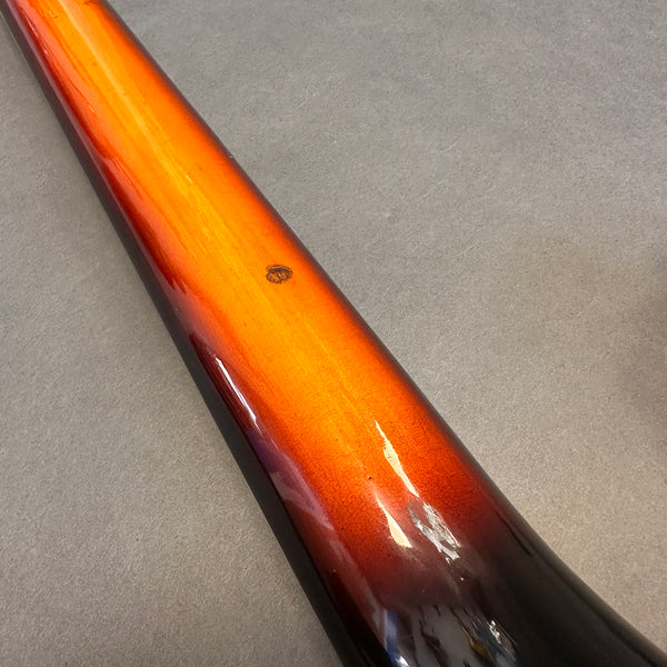 Close-up of guitar neck showing sunburst finish with minor wear and shine reflections on a gray background