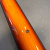Close-up of sunburst finish guitar neck with visible wood grain and a small chip on a gray background