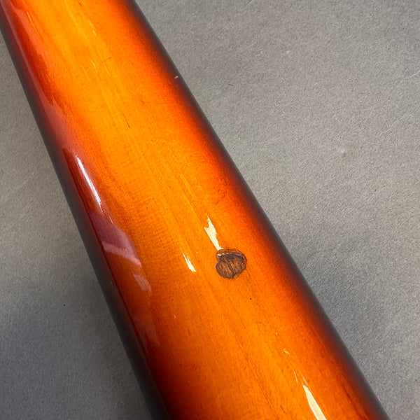 Close-up of sunburst finish guitar neck with visible wood grain and a small chip on a gray background