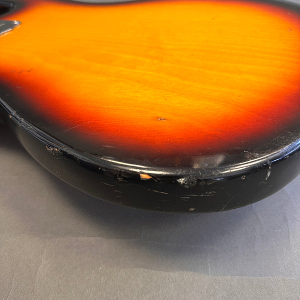Close-up of sunburst electric guitar body edge showing wear and scratches on black finish